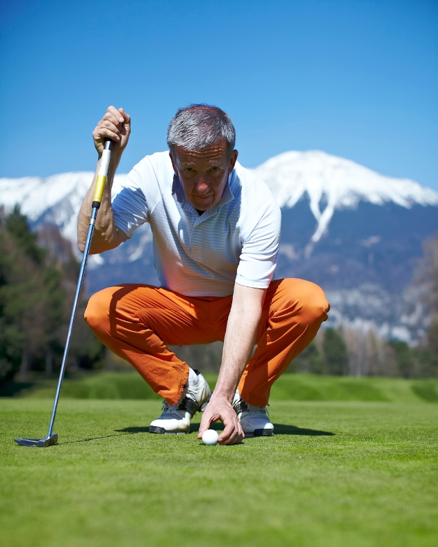 Man putting golf ball on ground 